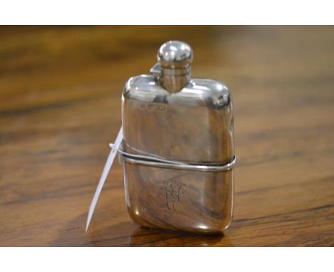 An Edwardian silver hip flask, London 1902, shaped for the hand, with screw top and detachable cup, engraved with a monogram.