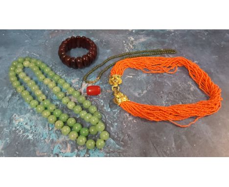 A cherry amber bracelet, 44g;&nbsp; a single bead, 4g;&nbsp; &nbsp;a 'Jade' necklace, 90cm long;&nbsp; another, 40cm long;&nb