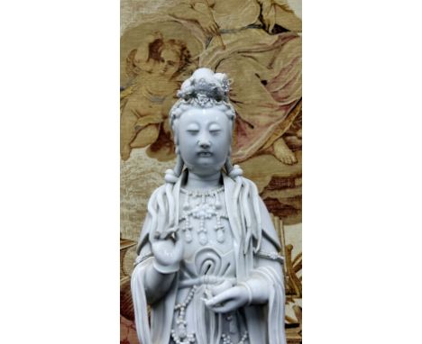 An 18th/19th century Chinese blanc de chine figure, of Guanyin, the deity modelled standing wearing draped flowing robes, ope
