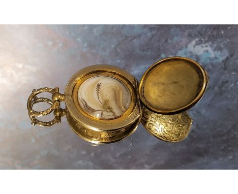 An early 19th century yellow metal circular mourning locket, the cover chased &amp; engraved with scrolls, monogrammed JS, re