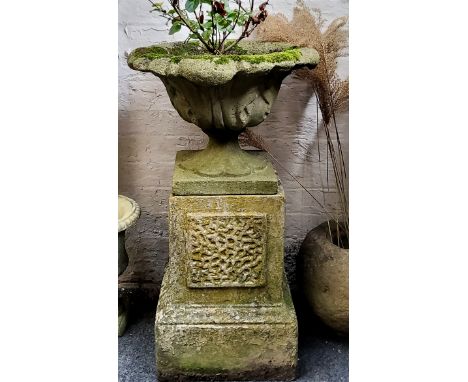 A reconstituted urn on stand, the scrolling acanthus planter sits on an outsplayed socle, stepped plinth base, signs of old e