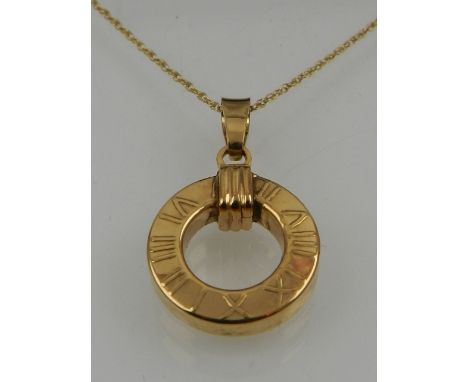 A 9 carat yellow gold circular pendant decorated with Roman numerals, suspended on a 9 carat yellow gold chain. 