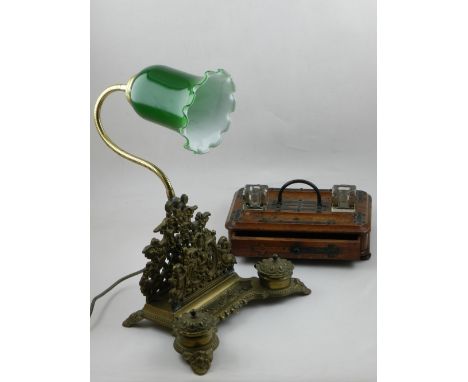 A brass desk inkstand, having twin inkwells and letter rack, decorated with cherubs, and later integrated reading light, toge