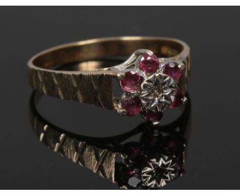 A 9ct gold ruby and diamond daisy cluster ring with cross hatched shoudlers, size S1/2.