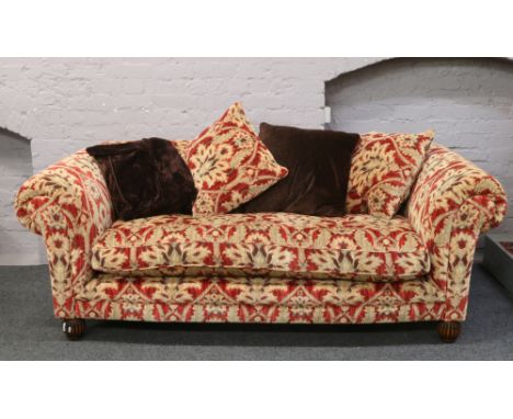 A good quality three seat sofa upholstered in red and gold velvet moquette upholstery raised on carved bun feet.