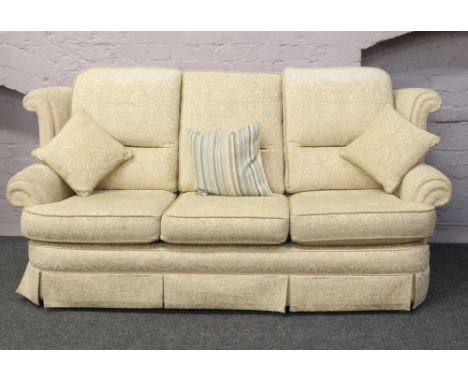 A cream upholstered three seat sofa with fire certificate.