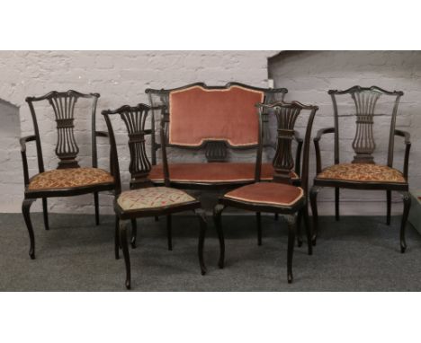 An Edwardian carved mahogany salon suite; upholstered two seat sofa, along with two carvers and two chairs raised on cabriole