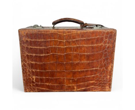 An early 20thC Edwardian Army & Navy crocodile skin suitcase, with cream silk lined interior and original key, the front stam
