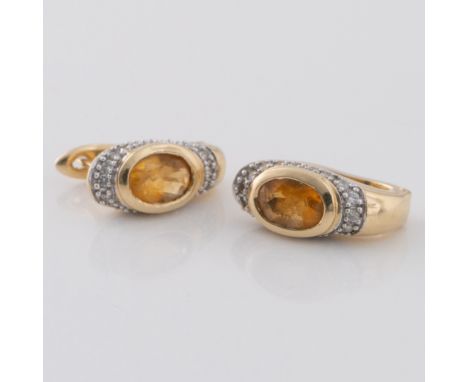 A pair of 14ct gold stud earrings, with a central stone surrounded by a band of chip diamonds, with a u-shaped clasp secured 