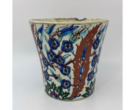 A Turkish Iznik tin glazed pot, decorated in light and dark blue, black, rust-orange and green with branches of blue flowers,