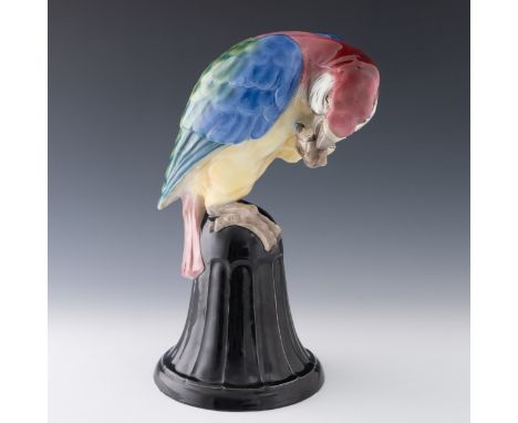 An early 20th century Austrian porcelain figure of a parrot, bird perched on a bell-shaped stand, finished in colours, with p