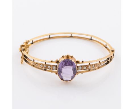 A 9ct gold bangle with amethyst and seed pearls, set with a band of graduated seed pearls and central stone, with push releas