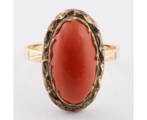 A polished coral wave form set in a yellow metal (marked 750 internally) mount form mount with a pie crust border, set in an,