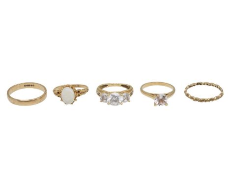 A 9ct opal ring, a three stone ring, two bands and one morefeaturing an oval opal in 9ct hallmarked gold, a three stone claw 