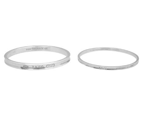 A pair of solid silver Tiffany bangles with Tiffany hallmarks to inside and outside of both the round and the oval bangle.(2)