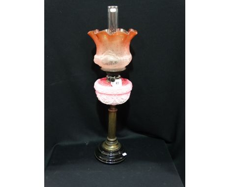 A Circular Based Brass Column Oil Lamp With Pink Tinted Reservoir And Etched Coloured Shade