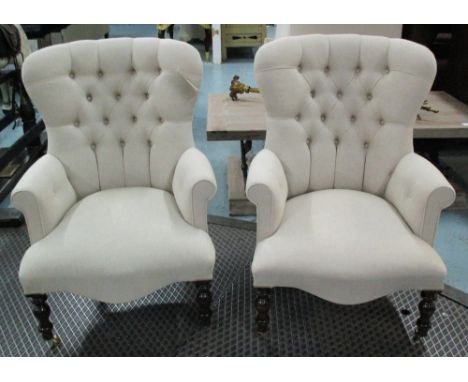 ARMCHAIRS, a pair, fawn linen covered with button backs on turned supports and castors, 66cm W. (2)