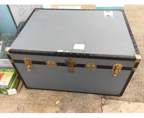 A LARGE GREY TRUNK WITH BRASS FITTINGS
