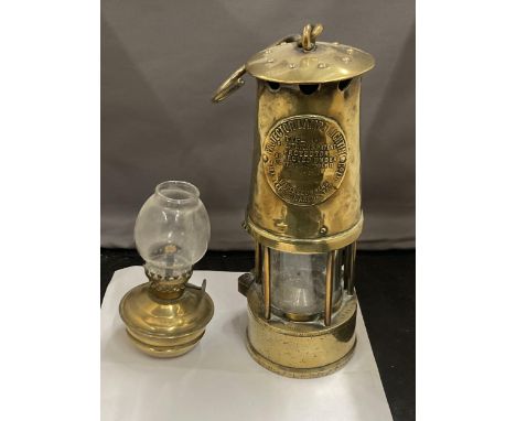 TWO BRASS LAMPS TO INCLUDE A VICTORIAN MINIATURE PARAFFIN LAMP WITH GLASS FUNNEL AND A PROJECTOR LAMP AND LIGHTING CO TYPE 6 
