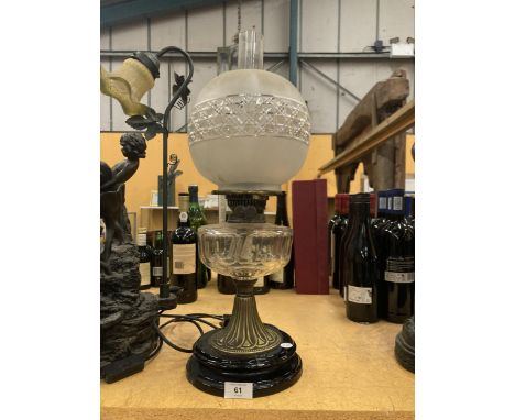 A VICTORIAN OIL LAMP WITH MILKY GLASS SHADE AND GLASS RESERVOIR ON A BRASS COLUMN AND BLACK PLINTH