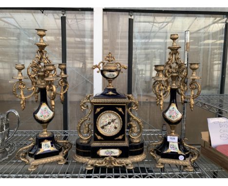 AN ORNATE AND DECORATIVE CERAMIC AND GILT THREE PIECE MANTLE CLOCK WITH CANDLESTICK GARNITURES, ENAMEL FACE AND BRASS DETAIL,