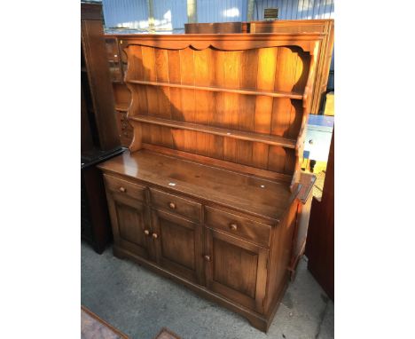 A BLONDE ERCOL DRESSER WITH THREE CUPBOARDS AND THREE DRAWERS TO BASE AND PLATE RACK, 53" WIDE