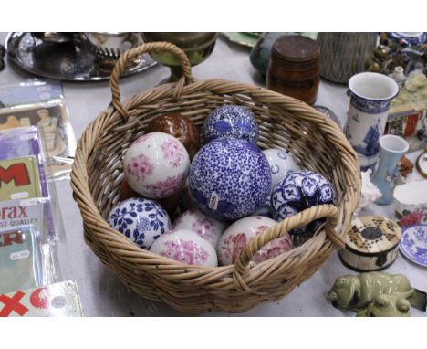 A COLLECTION OF VARIOUS SIZES OF PATTERNED CERAMIC BALLS IN A BASKET