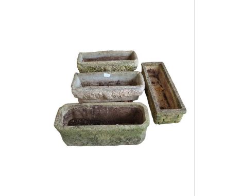 A Sandford stone trough planter together with a pair of trough planters with mask decoration and another planter with lion ma