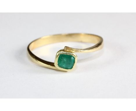 A yellow metal (tested min 18ct gold) emerald solitaire ring (K)