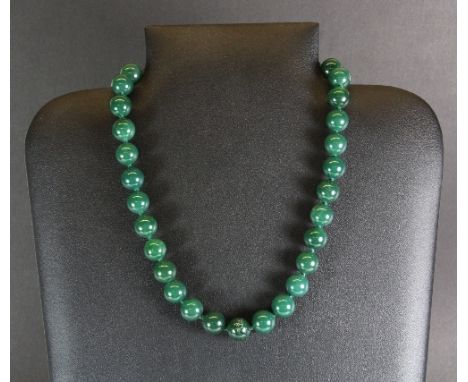 A single strand necklace of 12mm green jade / hardstone beads, L 44cm
