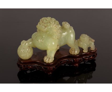 A celadon jade caving of a foo dog and young, 20th Century, Taishi Shaoshi, depicting a father and son playing, on a wooden s