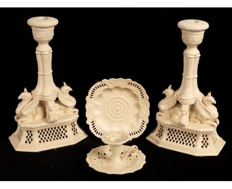 A pair of 'Royal Creamware' reproduction creamware figural candlesticks, each with a pair of griffin on a pierced base, a dis