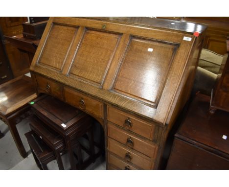 An early 20th Century oak bureau having panelled flap, interesting compartmental interior , heavy copper ring handles to draw