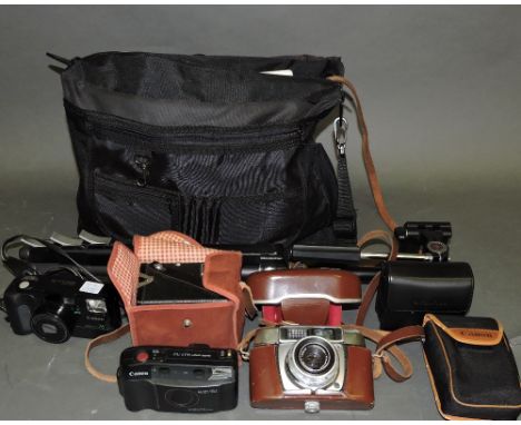 A quantity of cameras, including Praktica, Canon, a tripod and a telephoto lens; together with a pair of field glasses.  (qty