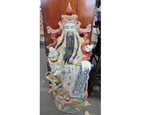 A large Chinese glazed porcelain Buddha, depicted standing holding a scroll over a coiled dragon, H. 96cm.