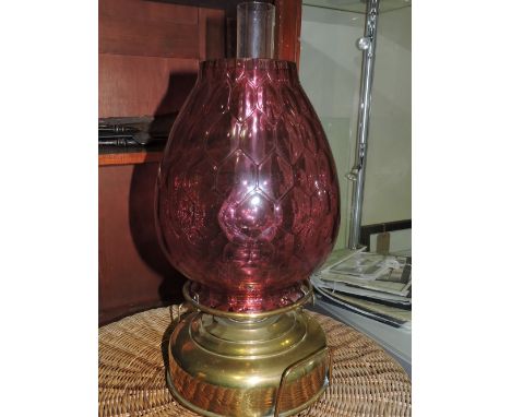 A late 19th century oil lamp, with a large brass reservoir and cranberry glass shade, H. 45cm.