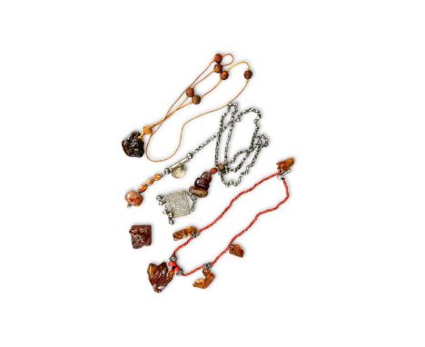 Amber Carvings, 19/20th century,  comprising an inscribed amber netsuke with a dog, and two Chinese necklaces with animals in