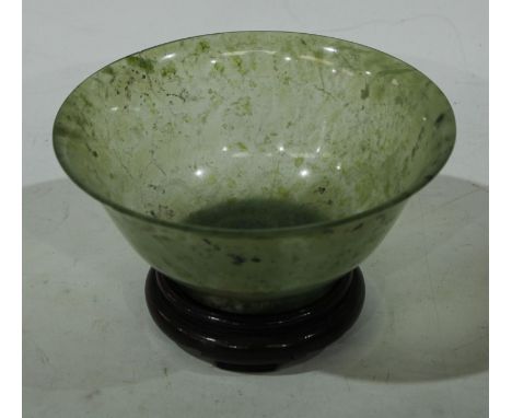 A Chinese green jade flared circular bowl, quite plain, 12.5cm diam, hardwood stand 