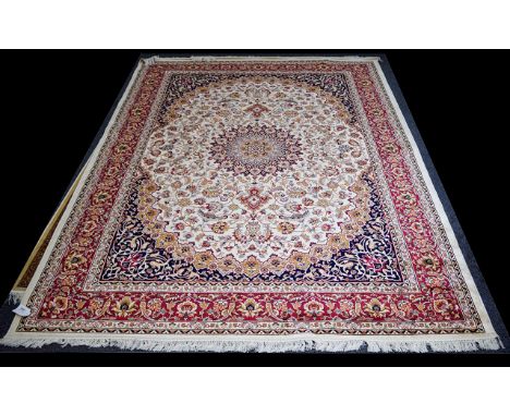 A Large Woven Silk Hekiz Carpet Finley woven rug on beige ground with intricate scrolling floral and foliate design in red, b