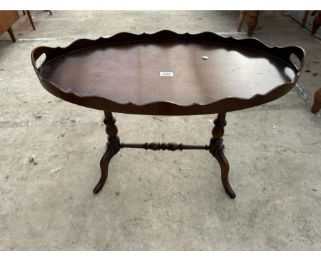 AN OVAL OCCASIONAL TABLE WITH CARRYING HANDLE ON A PEDESTAL FRAME 