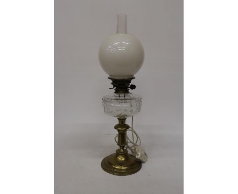 A 19TH CENTURY OIL LAMP CONVERTED TO ELECTRIC WITH A BRASS BASE, CLEAR CUT GLASS RESERVOIR, MILK GLASS SHADE AND GLASS FUNNEL