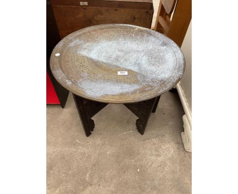 AN INDIAN BRASS TABLE ON A FOLDING HARDWOOD BASE 22.5" DIAMETER 