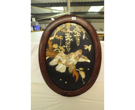 Oval decorated lacquer framed Eagle in relief in mother of pearl and bone perched on a wooden branch with blossoms and leaves