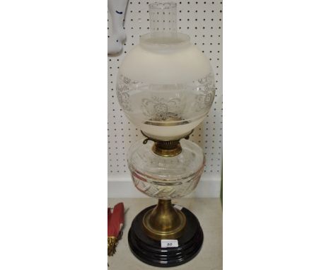 An early 20th century oil lamp, clear glass reservoir, black plinth