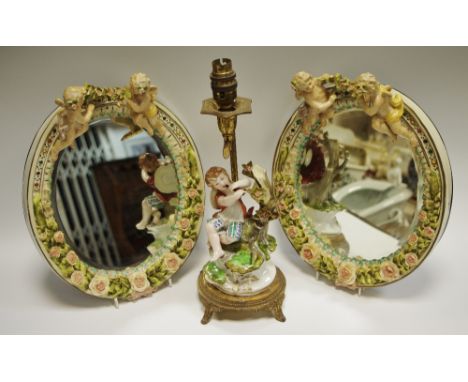 A pair of continental porcelain oval wall mirrors, applied in relief with cherubs and flowers, 30cm; a Spanish porcelain pipe