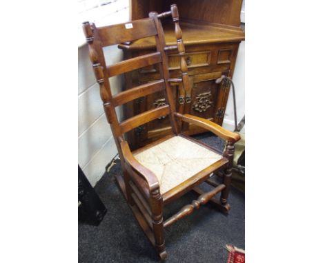 An unusual 19th century ash and elm rocking chair with handles to flanks, ladder back splats, rush seat with turned supports 