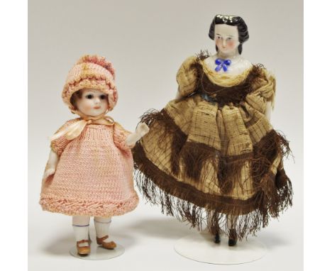 A German all bisque doll`s house doll, with  blue eyes, closed mouth, brown wig, painted socks and shoes, 10cm tall;  another