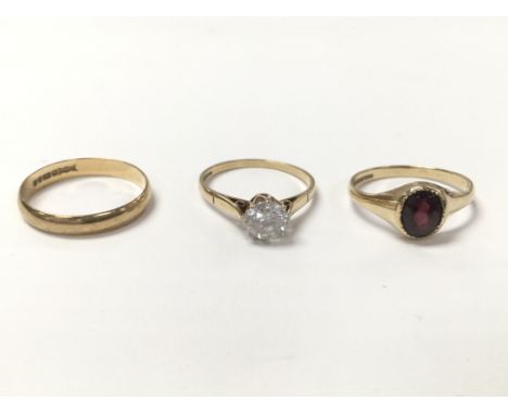 A collection of three rings - one gold ring set with A solitaire CZ (Approx between ring sizes N and O) one gold wedding band