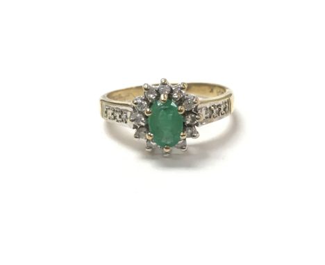 A 9 carat gold ring set with an emerald flanked by diamonds. Measuring approximately between ring size M and N.