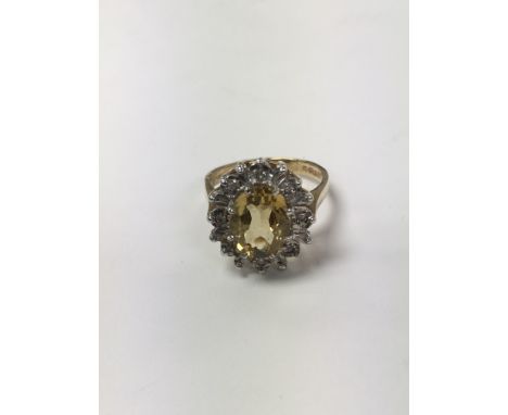 A 9 carat gold ring set with an oval yellow citrine and flanked by chip diamonds. The approximate ring size is between O and 